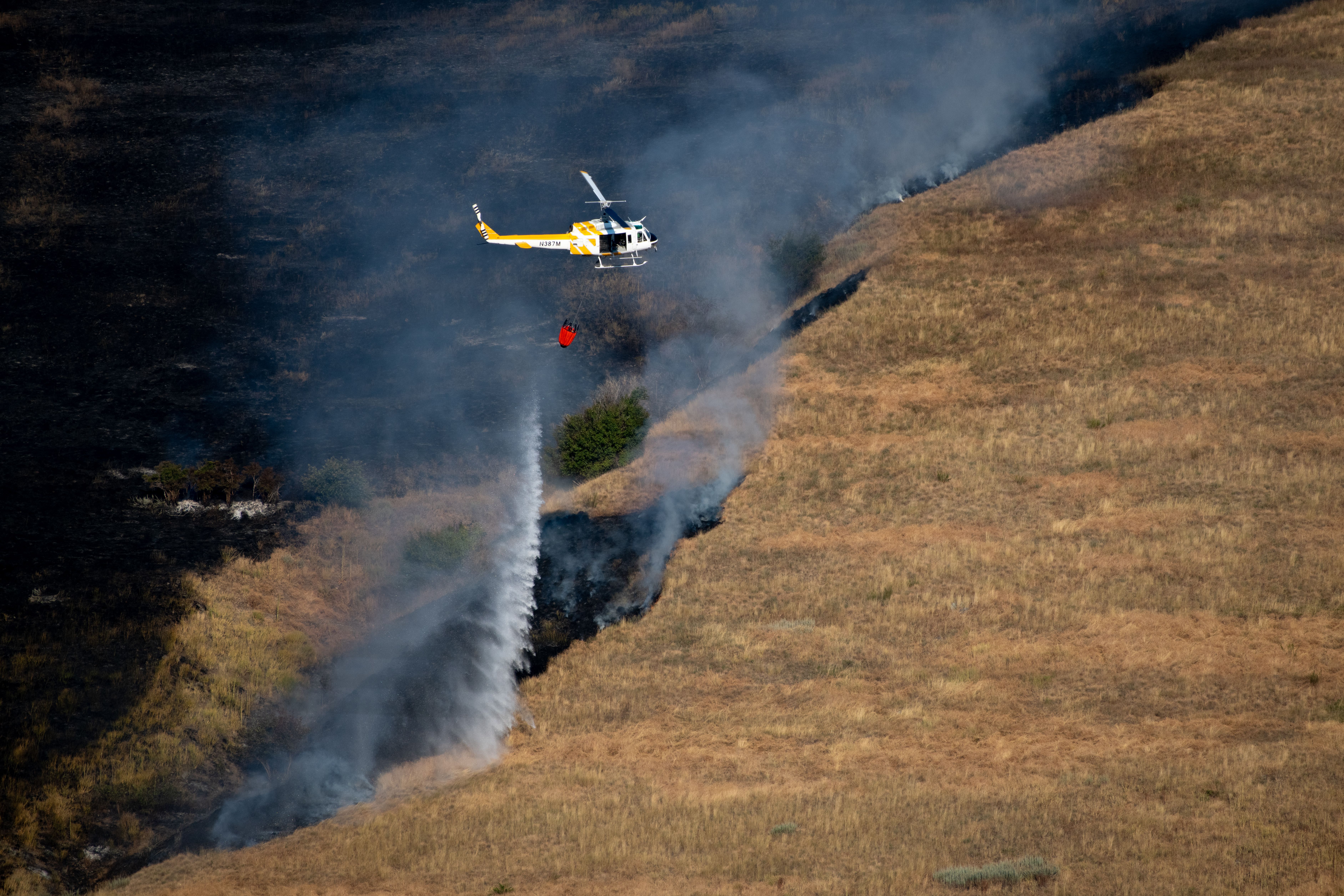 A rescue helicopter landing in a remote Montana mountain wilderness valley during an emergency evacuation