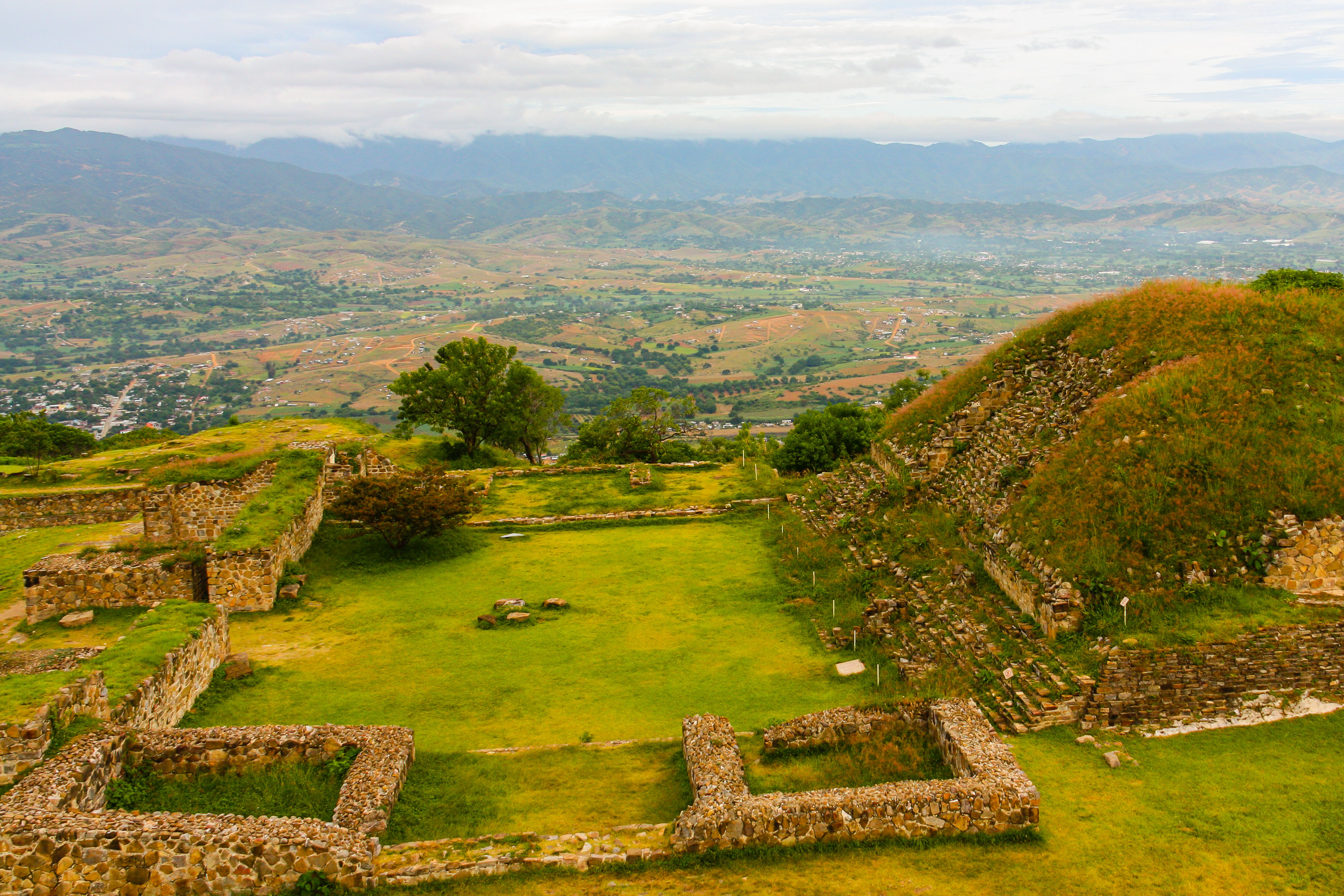 Aerial view of the ancient Zapotec ruins of Monte Albán perched on a flattened mountain ridge overlooking the wide green valley of Oaxaca