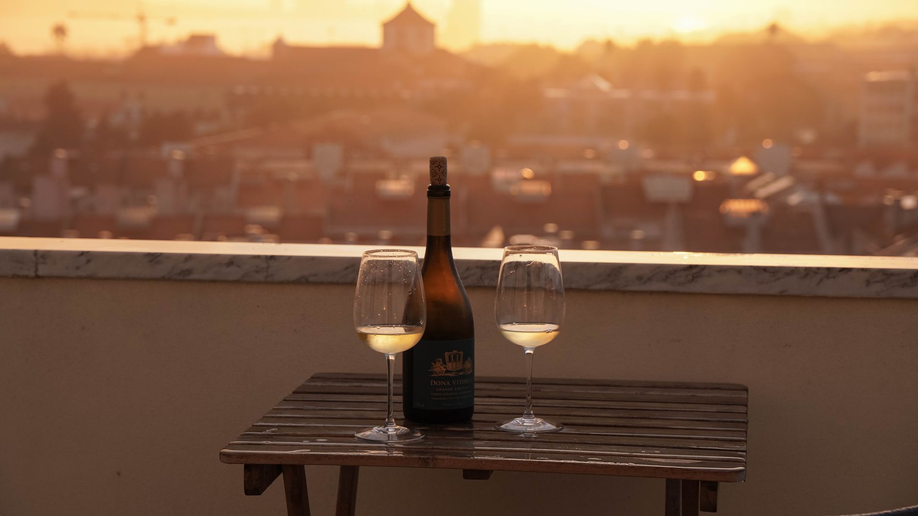 Relax with wine on a Lisbon rooftop as the sun sets over the cityscape. Perfect for romantic evenings.