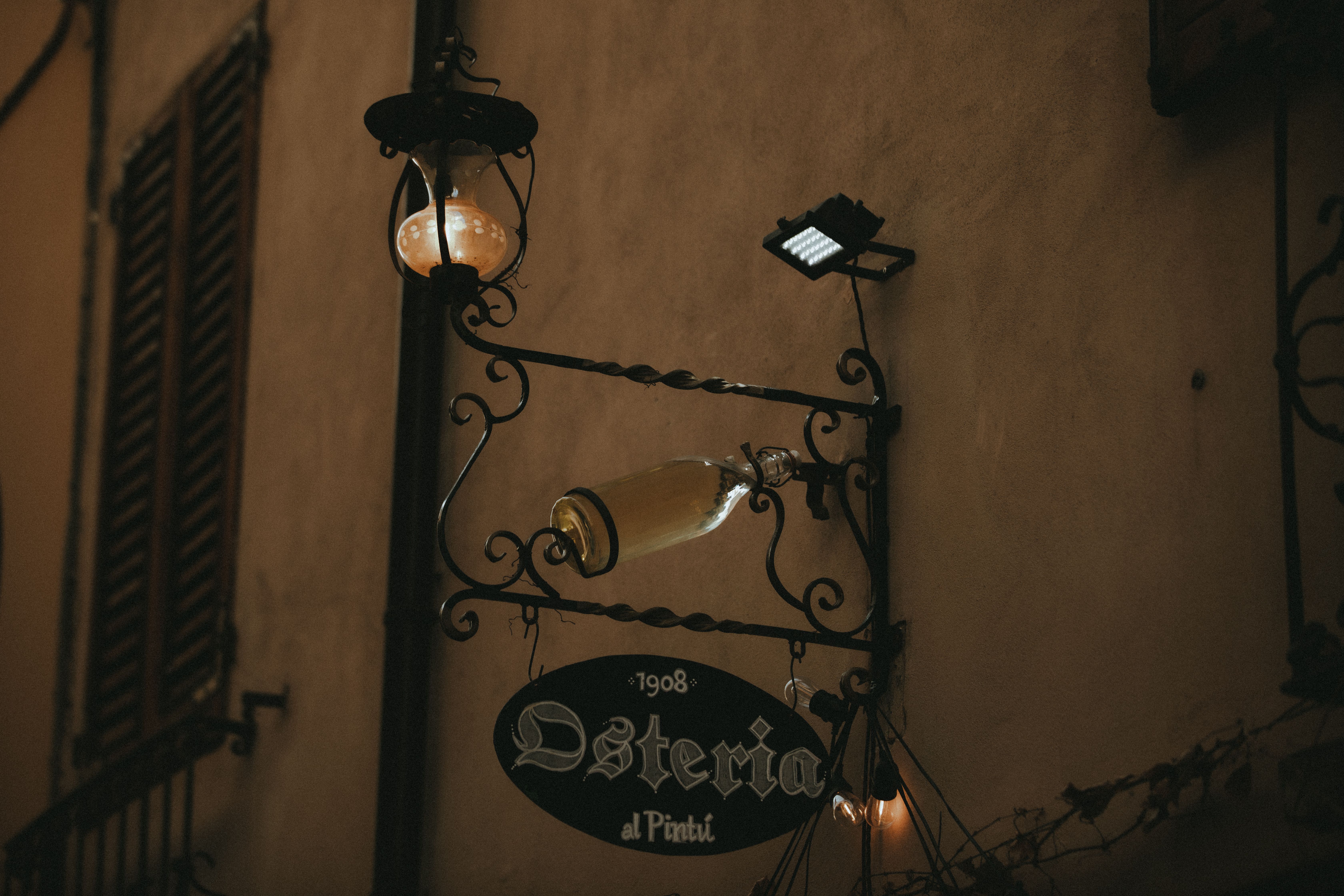 The dimly lit, centuries-old interior of Osteria del Sole in Bologna, with wooden tables crowded with locals drinking wine and sharing market food beneath low ceilings and antique shelving lined with bottles