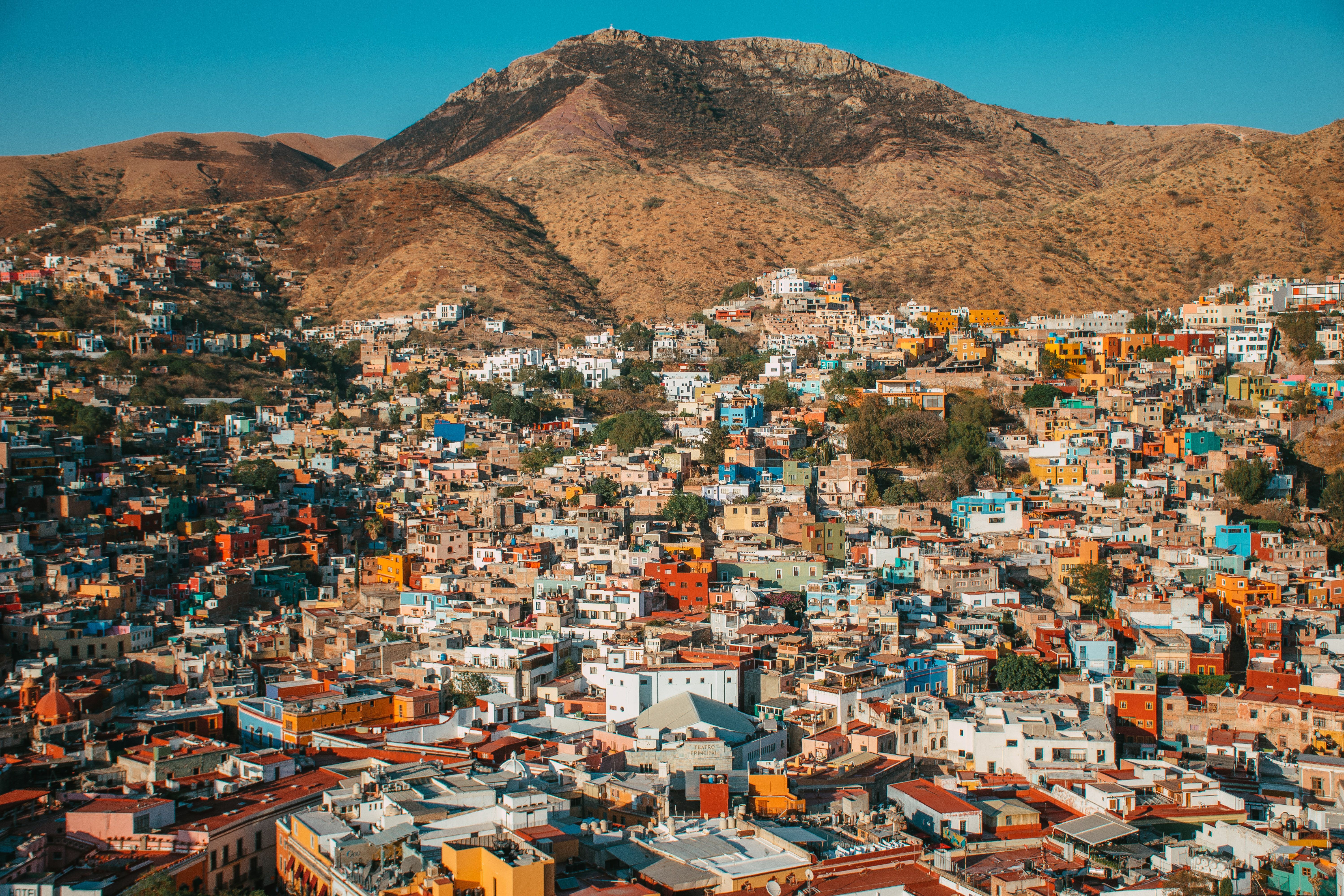 Narrow alley in Guanajuato Mexico with vividly colored pink and yellow colonial houses stacked up the hillside and balconies nearly touching overhead
