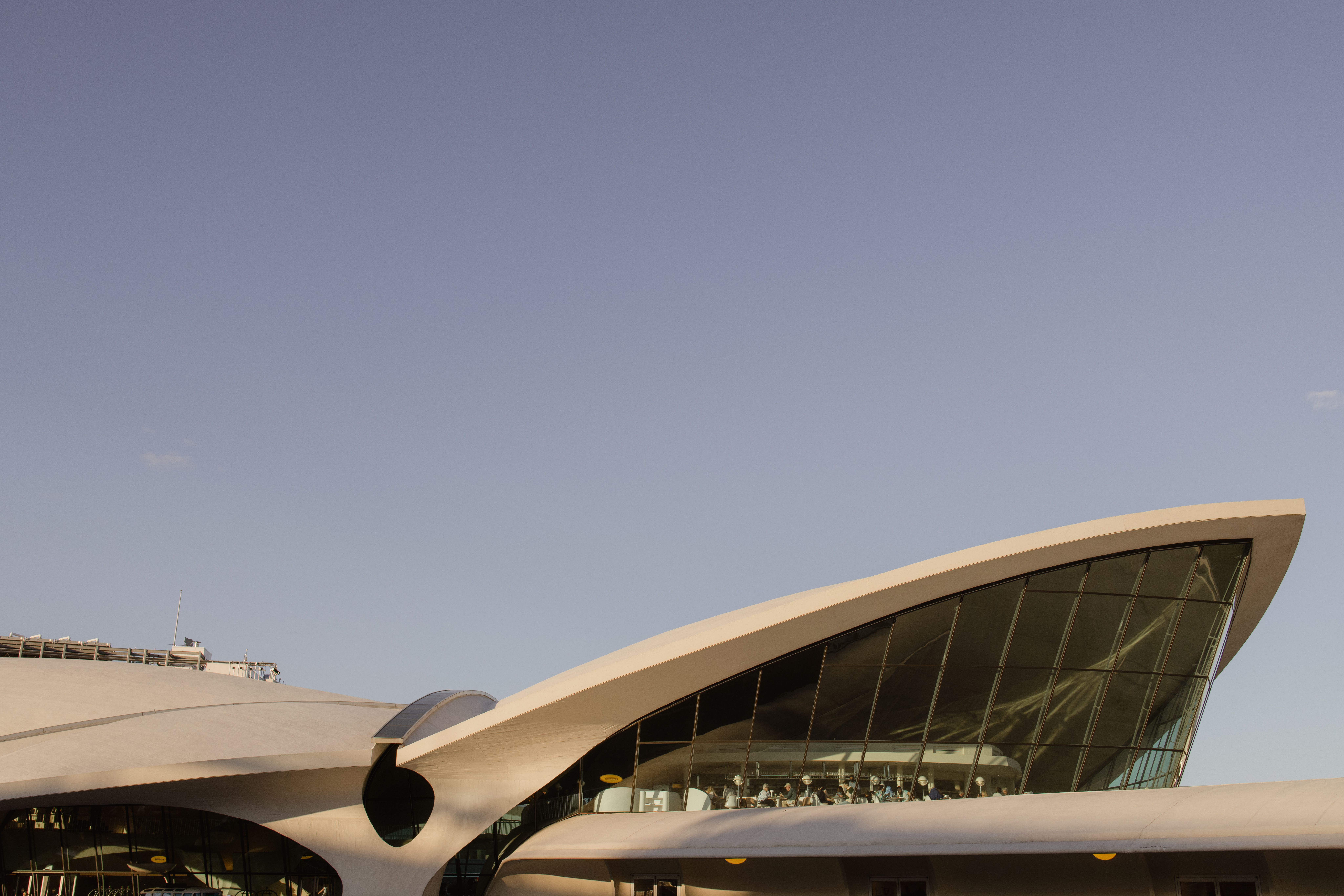 Denver International Airport's Jeppesen Terminal exterior at golden hour, with its signature white tensile roof peaks glowing against a warm Colorado sky