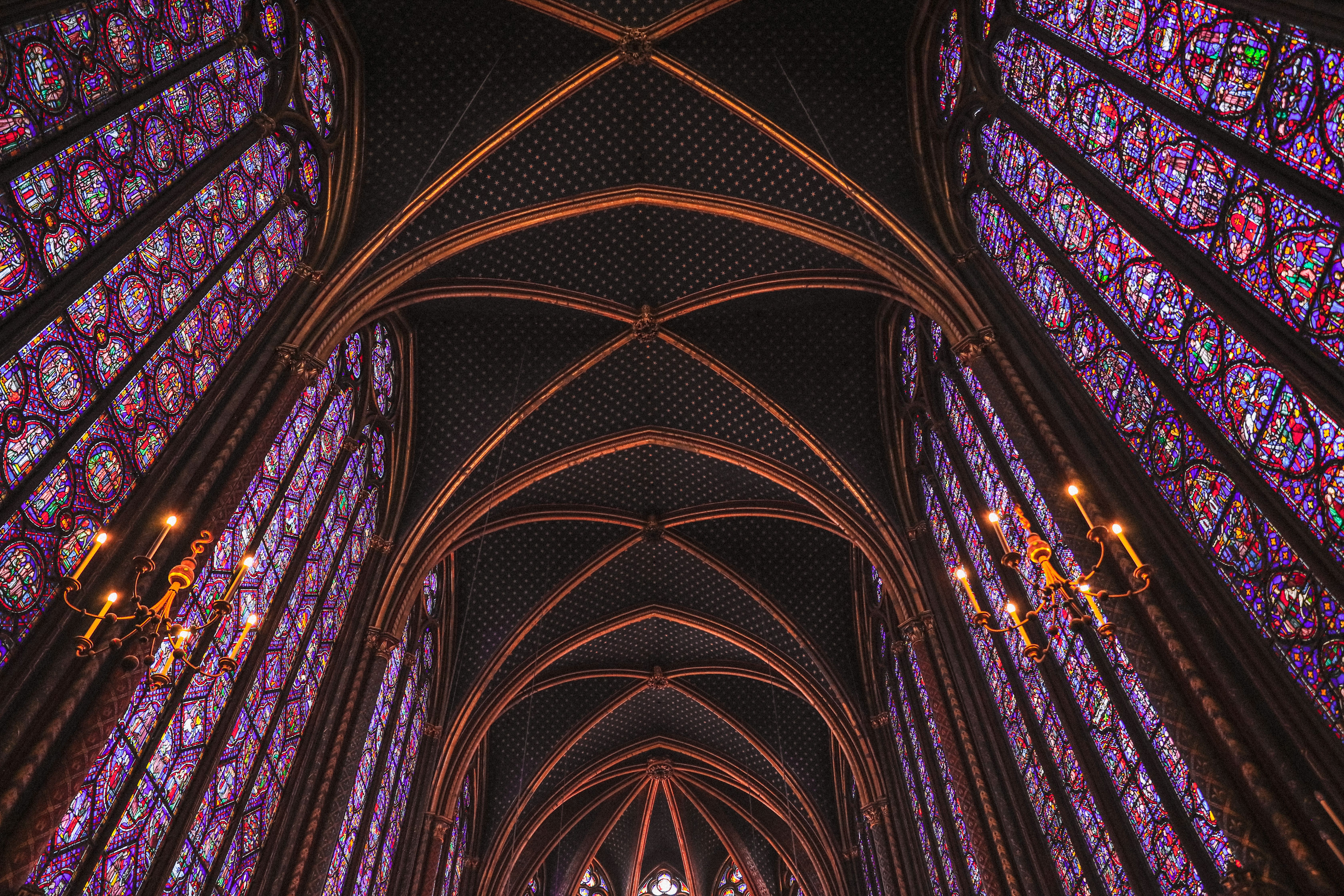 Interior of Sainte-Chapelle in Paris showing soaring Gothic architecture with floor-to-ceiling stained glass windows in blue and red flooding the chapel with colored light