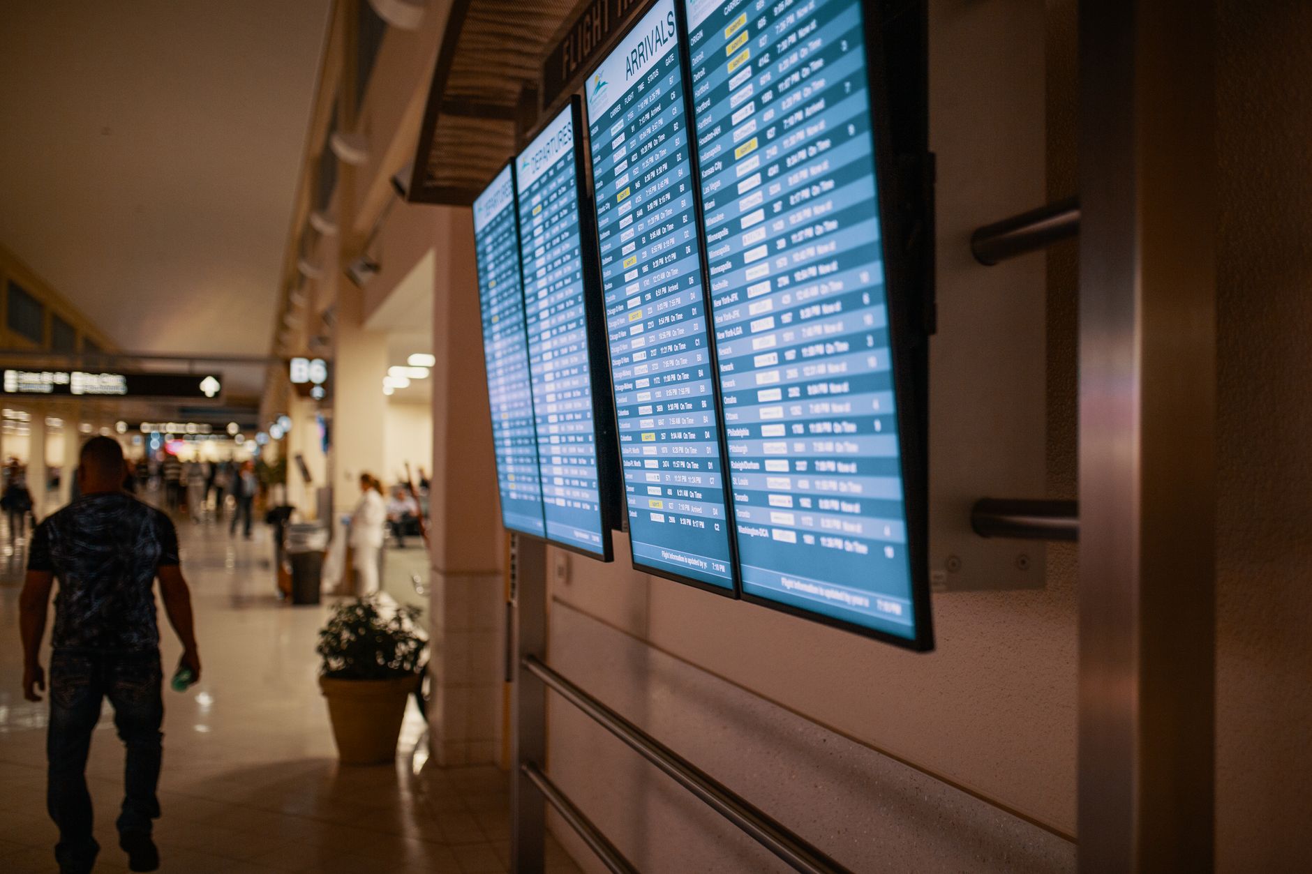 Passenger looking at airport departure board showing flight delays