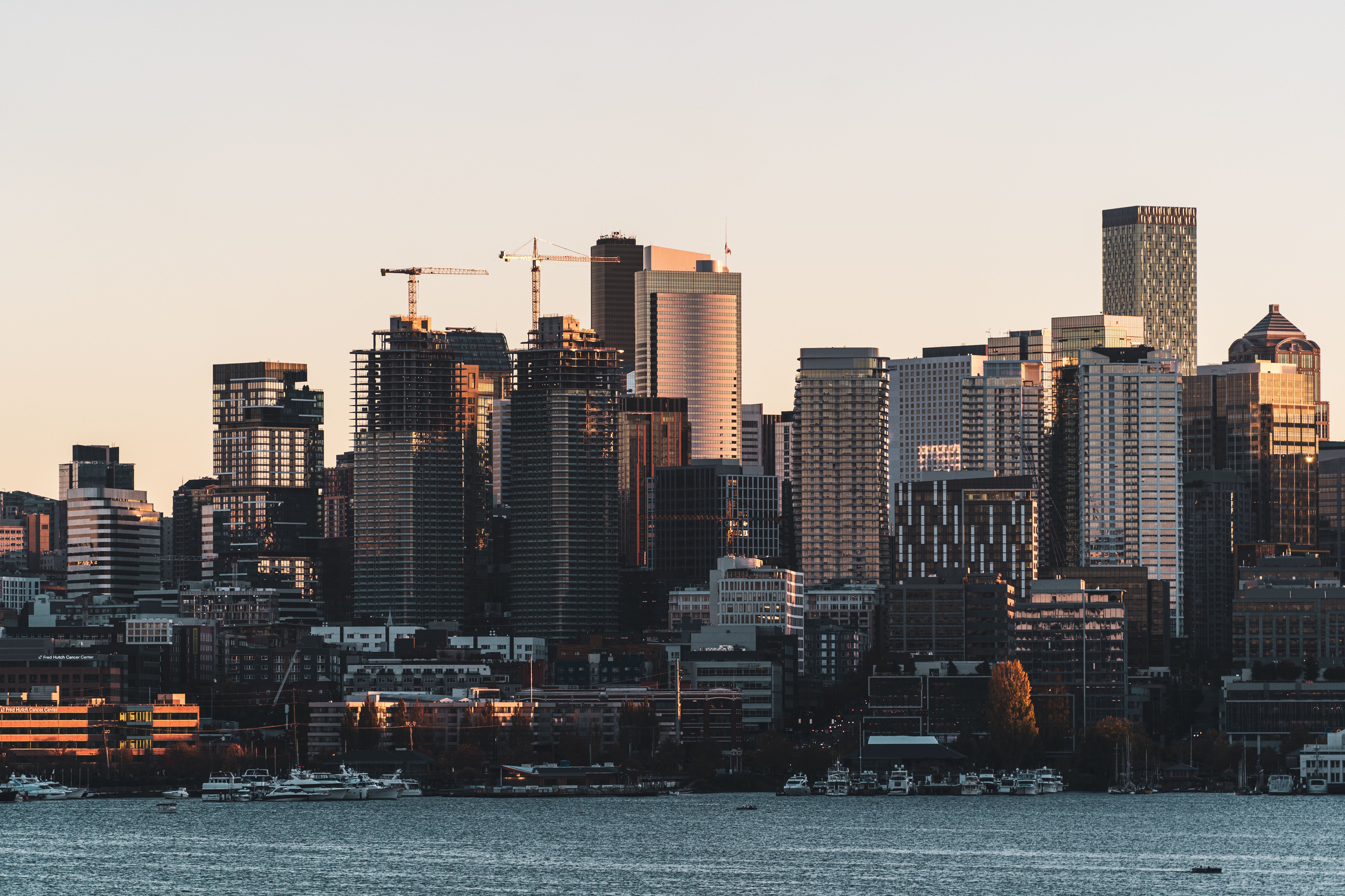 Twilight aerial view of downtown Seattle skyline with warm golden light reflecting off glass hotel towers and the waterfront visible in the background