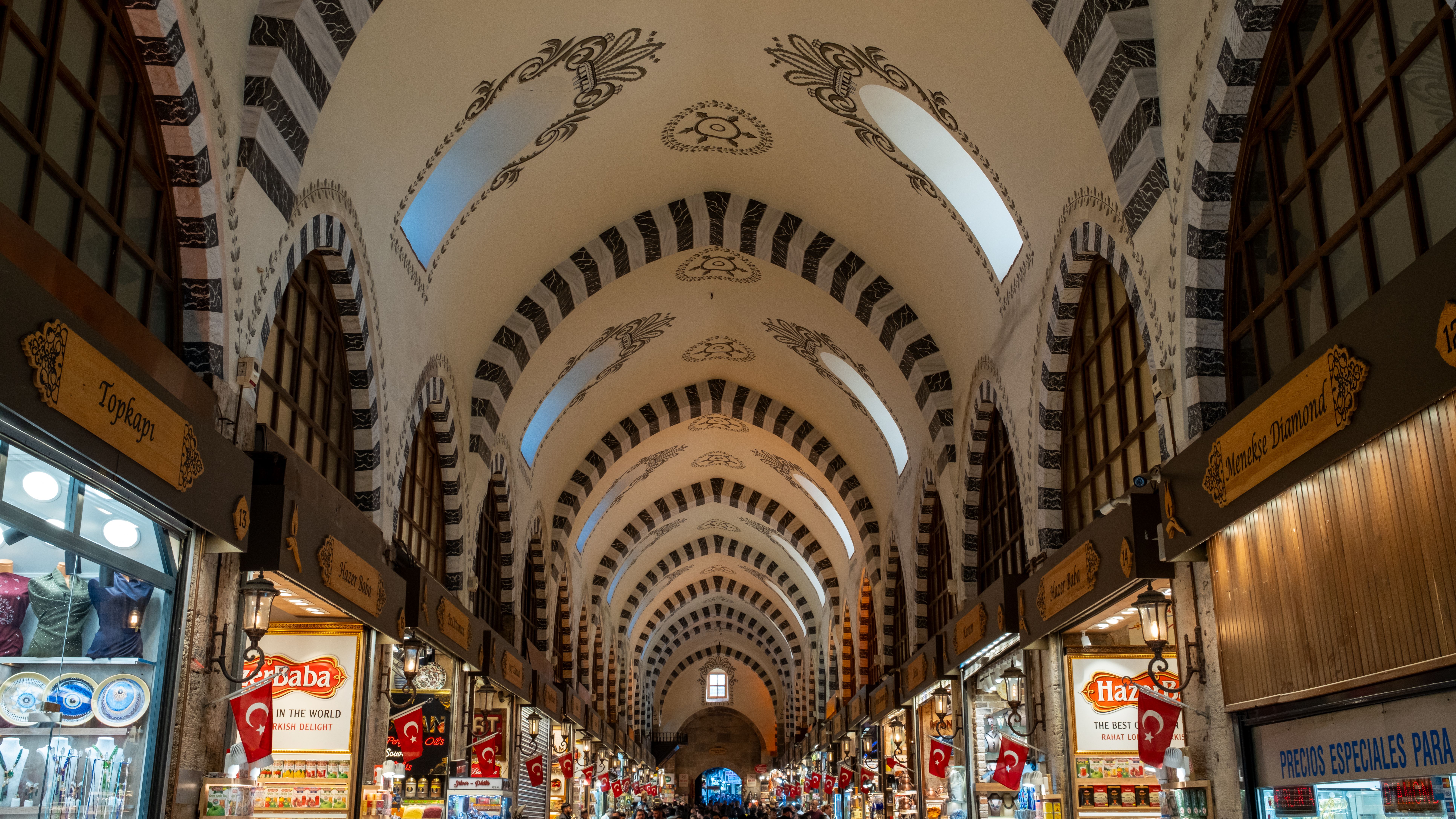 Interior of Istanbul's Spice Bazaar with vaulted stone arches, warm golden morning light, and colorful mounds of spices displayed in wooden stalls