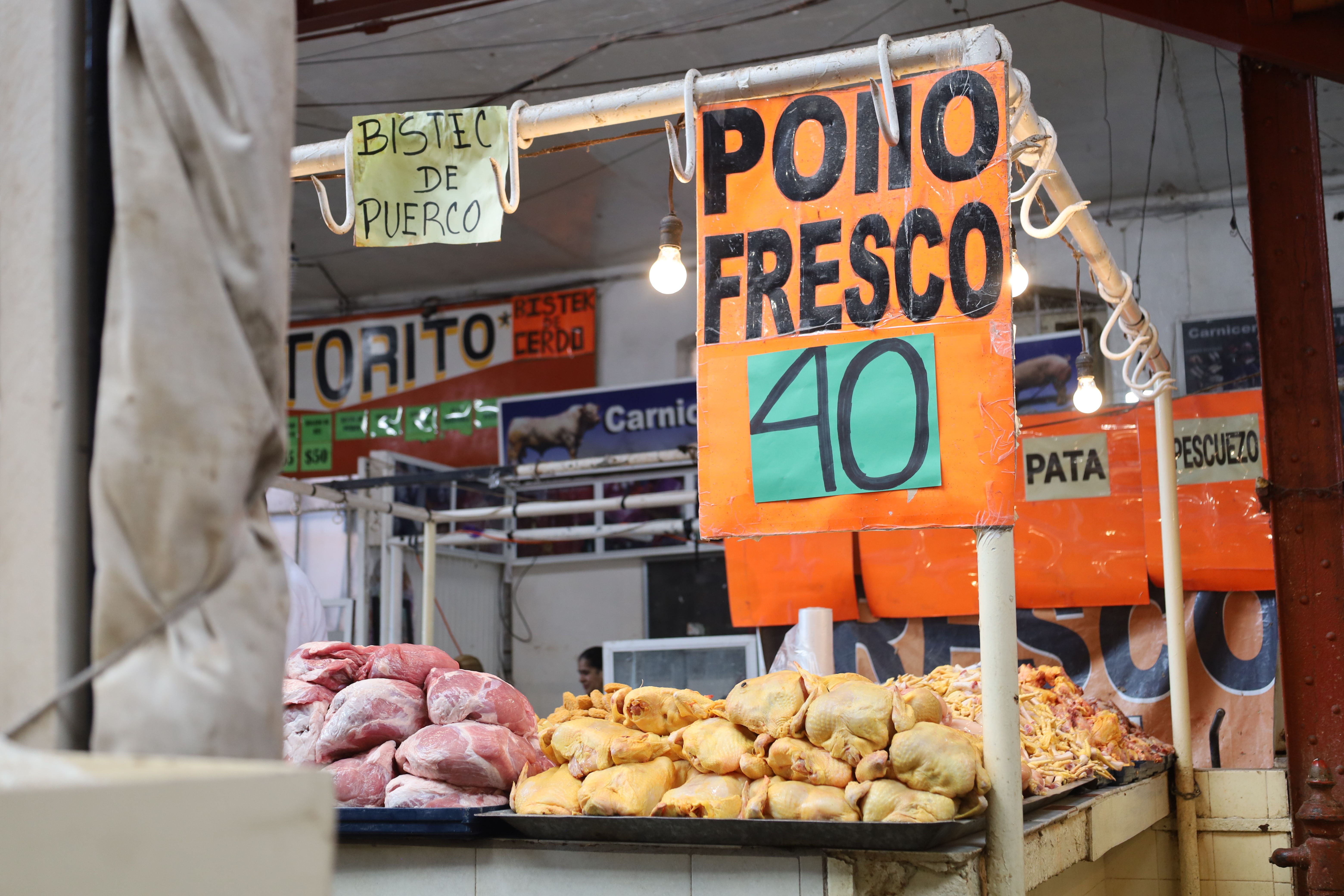 Colorful market stalls inside Mercado de Surquillo in Lima with vendors selling fresh produce, chili peppers, and prepared food at comedor counters