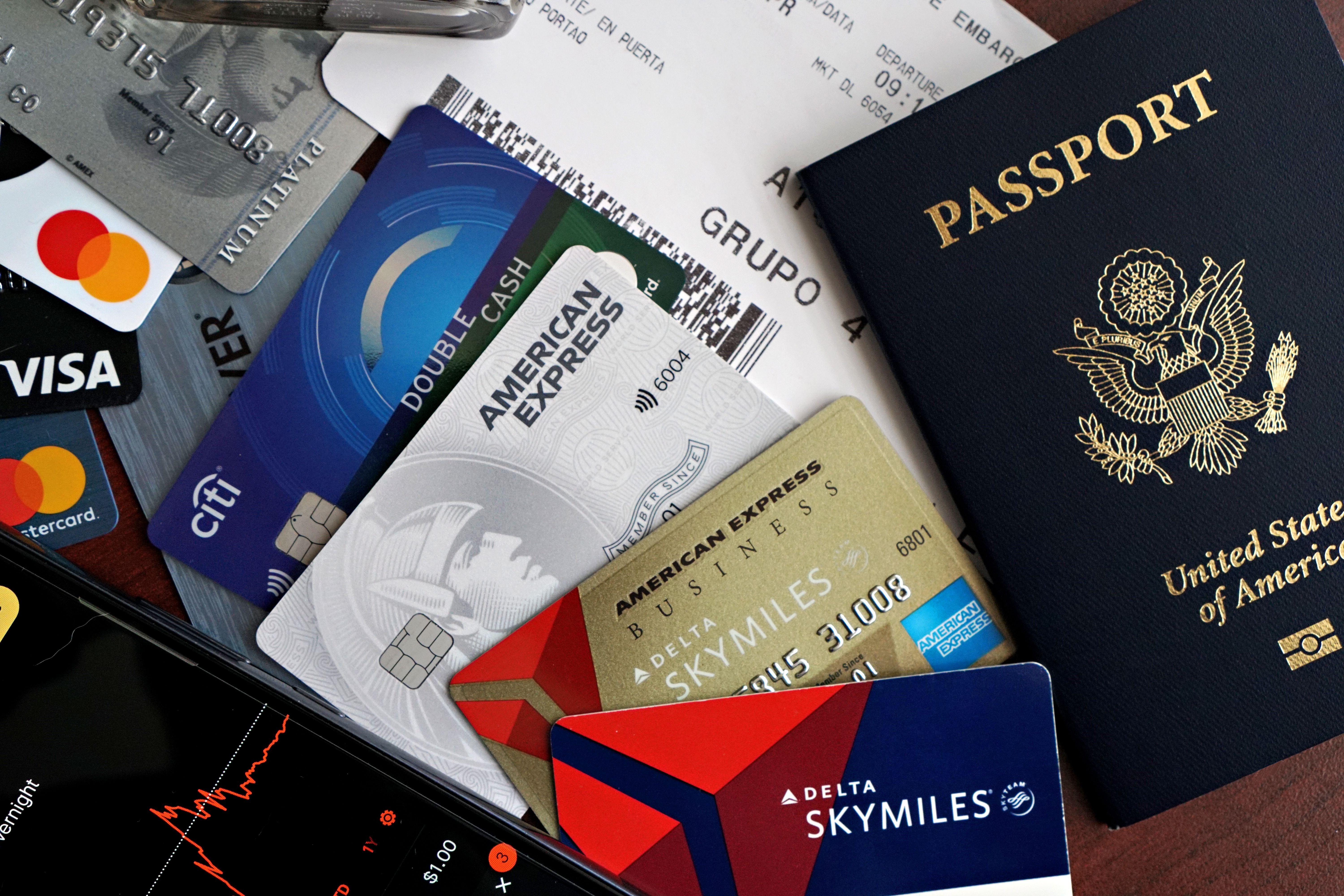 Travel insurance policy documents fanned out beside a passport and airline boarding pass on a wooden desk