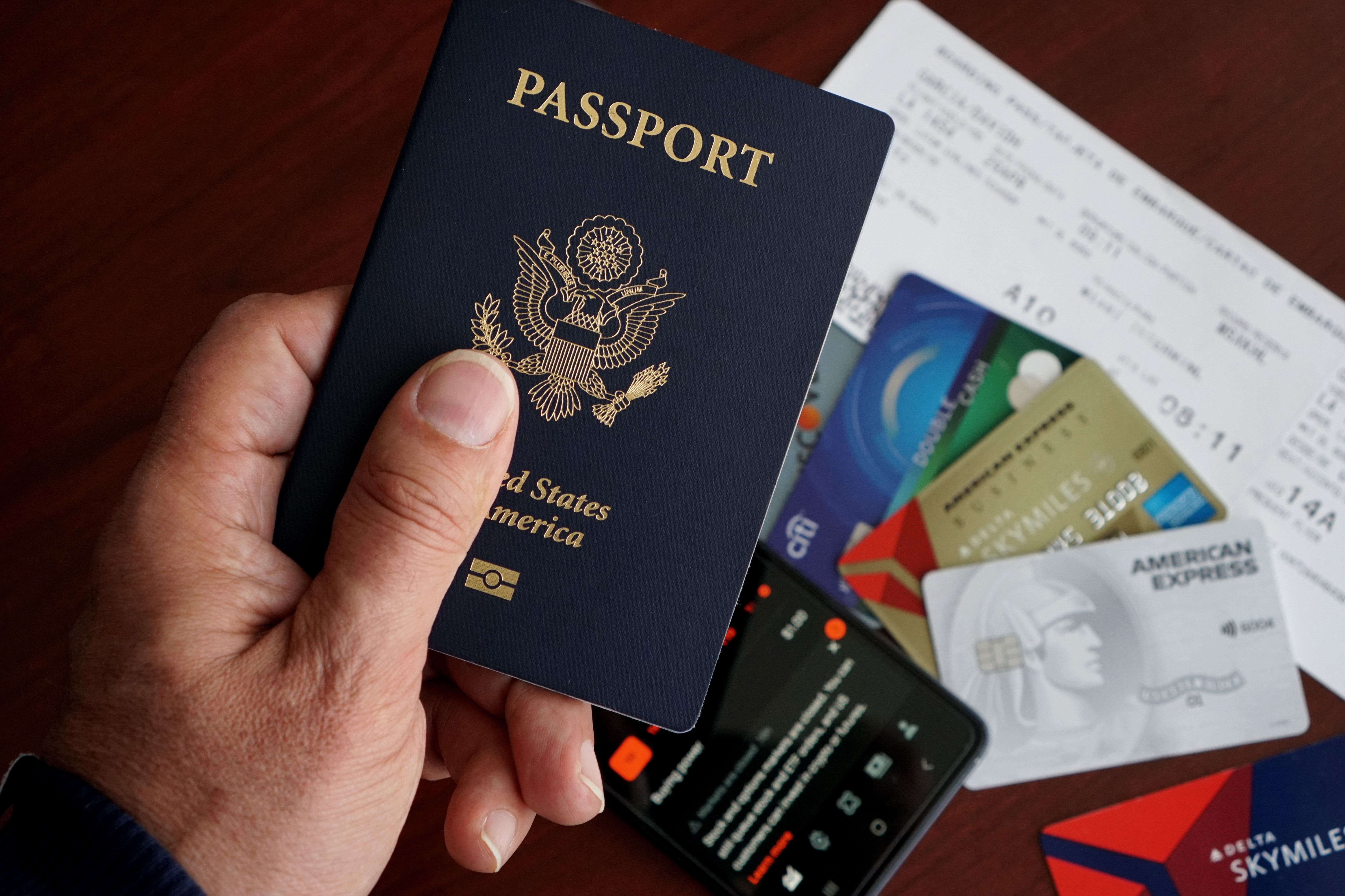 A printed airline ticket and hotel confirmation documents on a travel planning workspace with a passport and pen