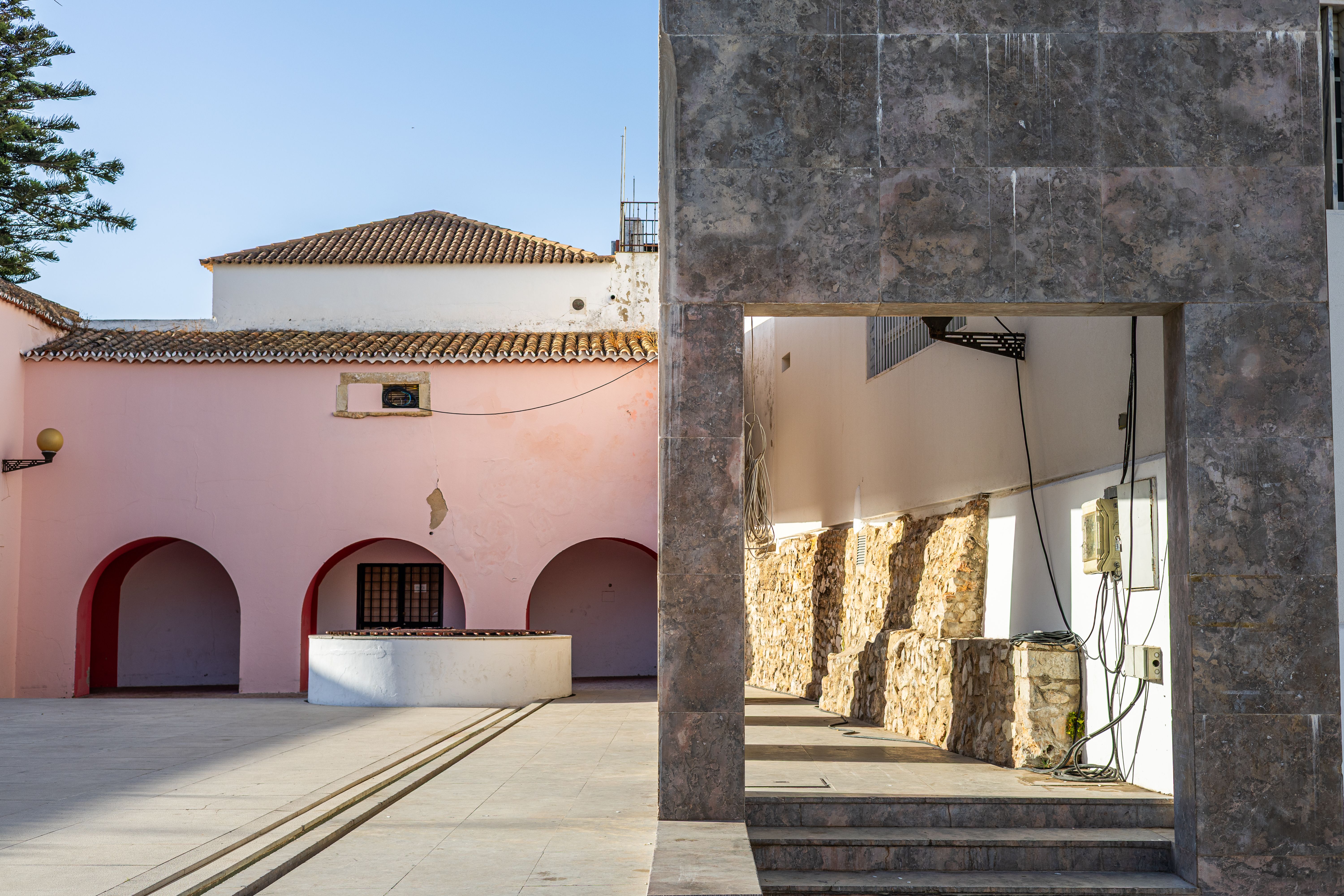 A large Portuguese villa courtyard with a pool and shaded seating where family members of different ages gather at leisure
