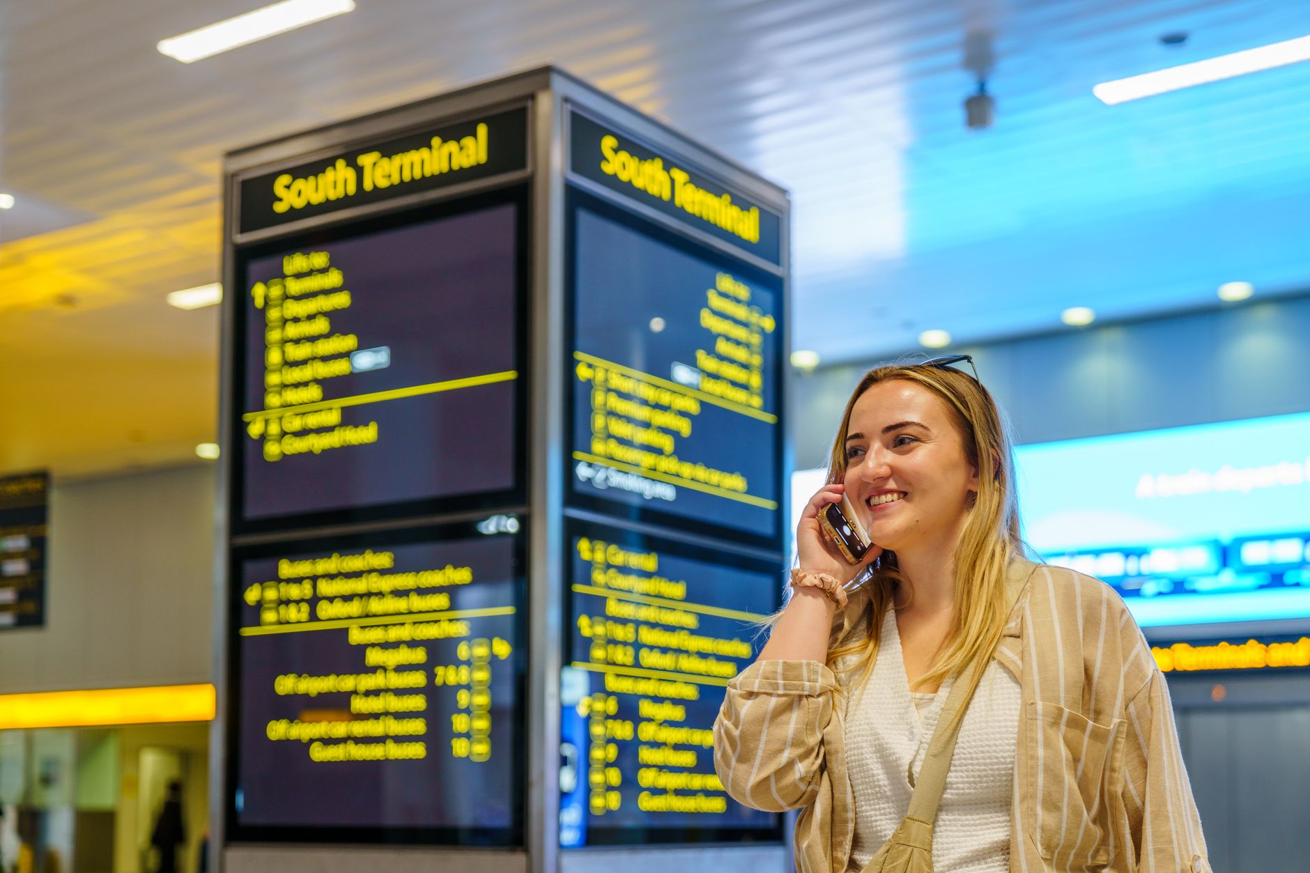 Traveler on phone call in bright airport terminal
