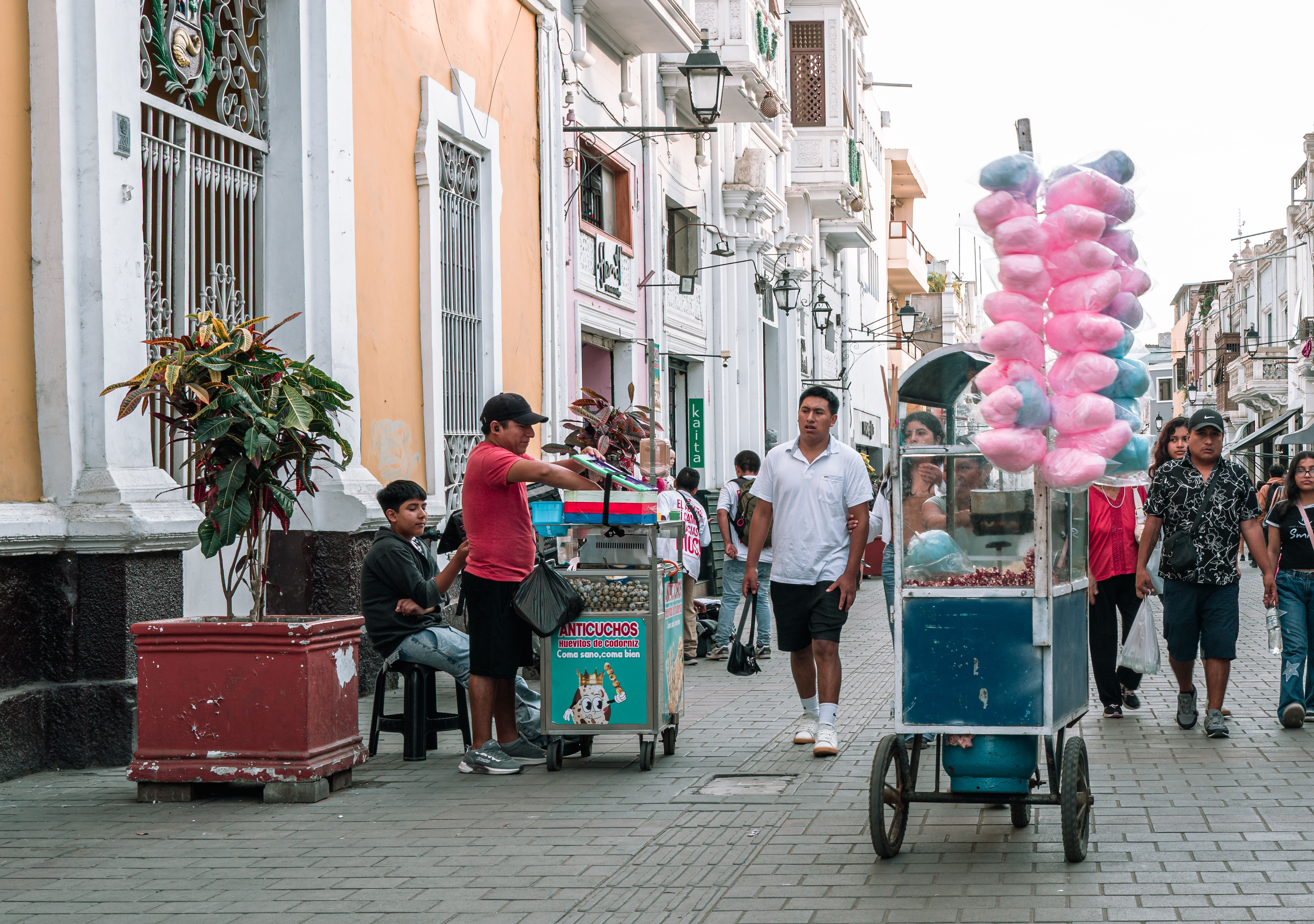 A street vendor grilling anticuchos beef heart skewers over a charcoal cart on a Lima sidewalk at night in the Barranco neighborhood