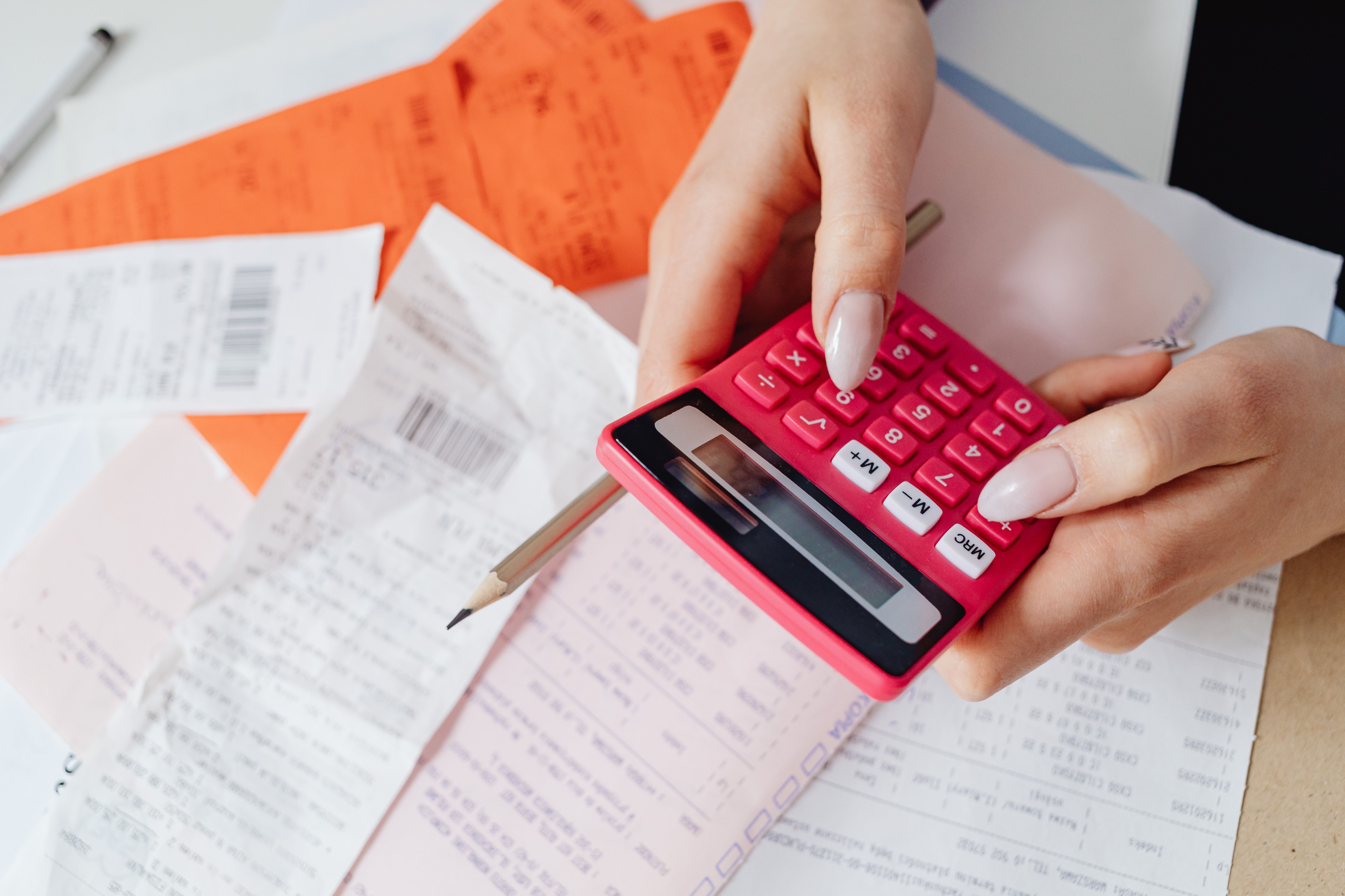 Travel insurance comparison documents spread on a desk alongside a calculator, passport, and handwritten coverage notes