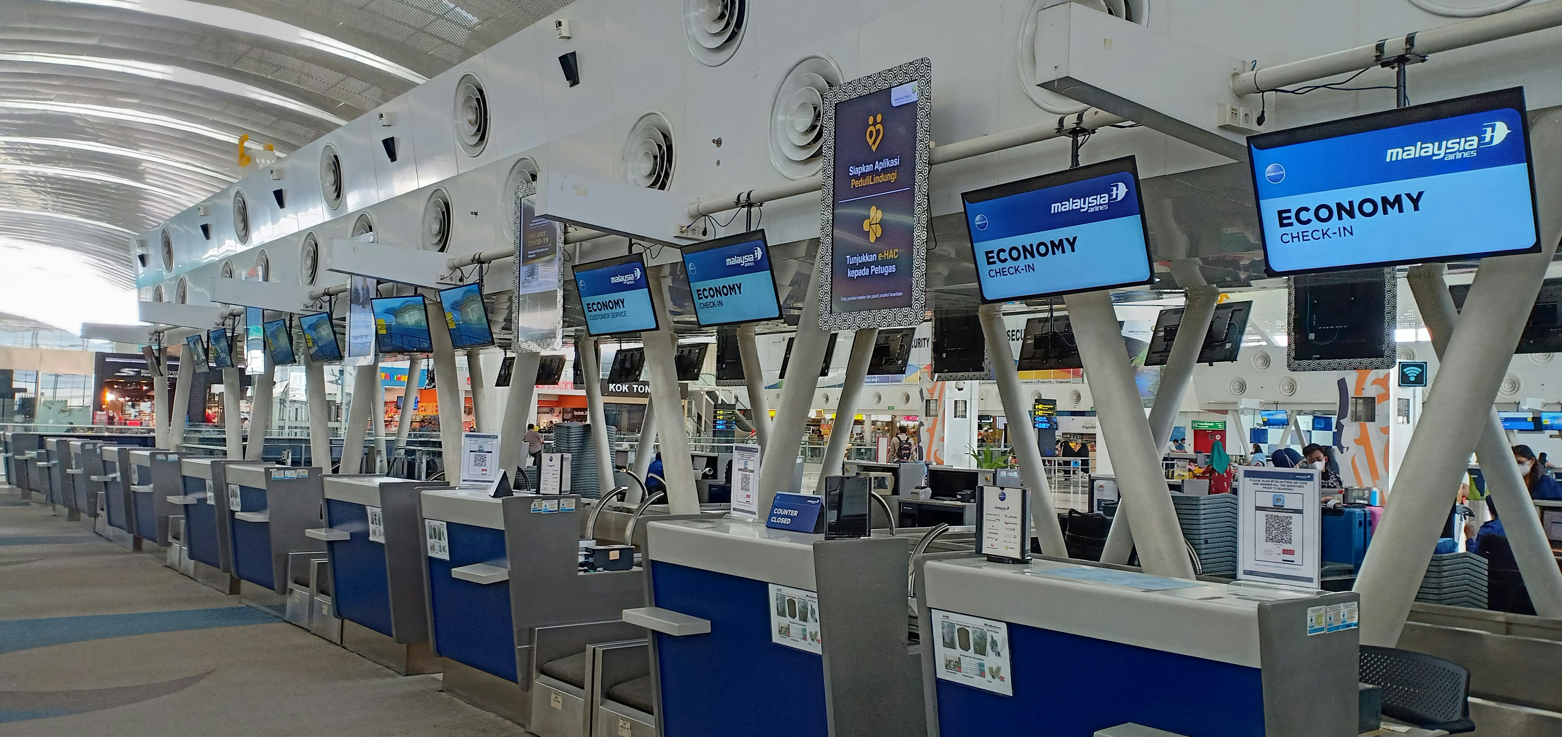 Traveler speaking with airline agent at service desk in airport terminal
